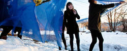 Students installing blue fabric sculpture outdoors in snow