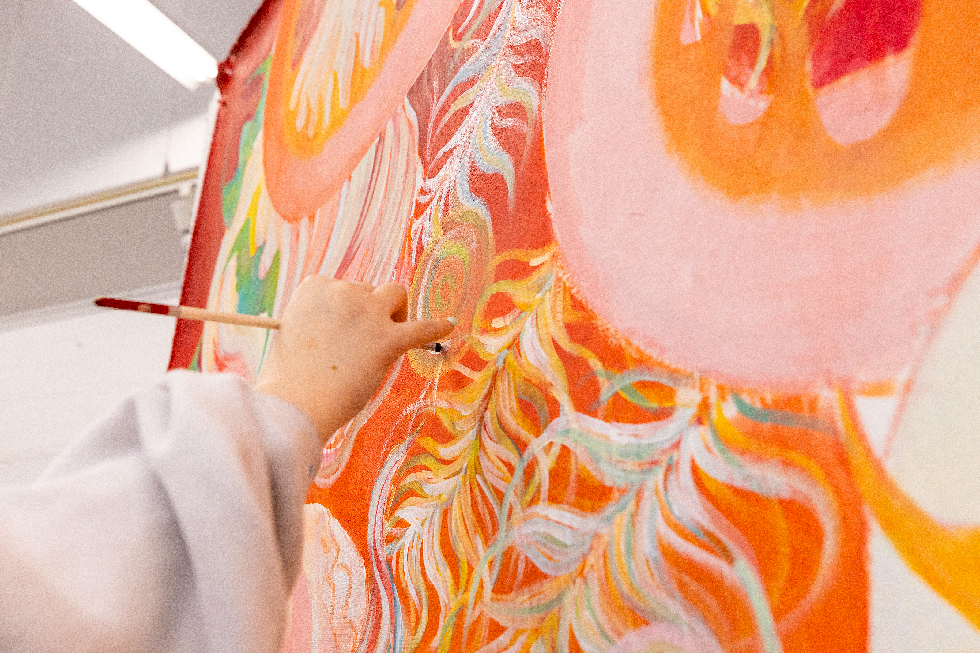 close-up of a hand holding a paint brush and working on an orange dragon