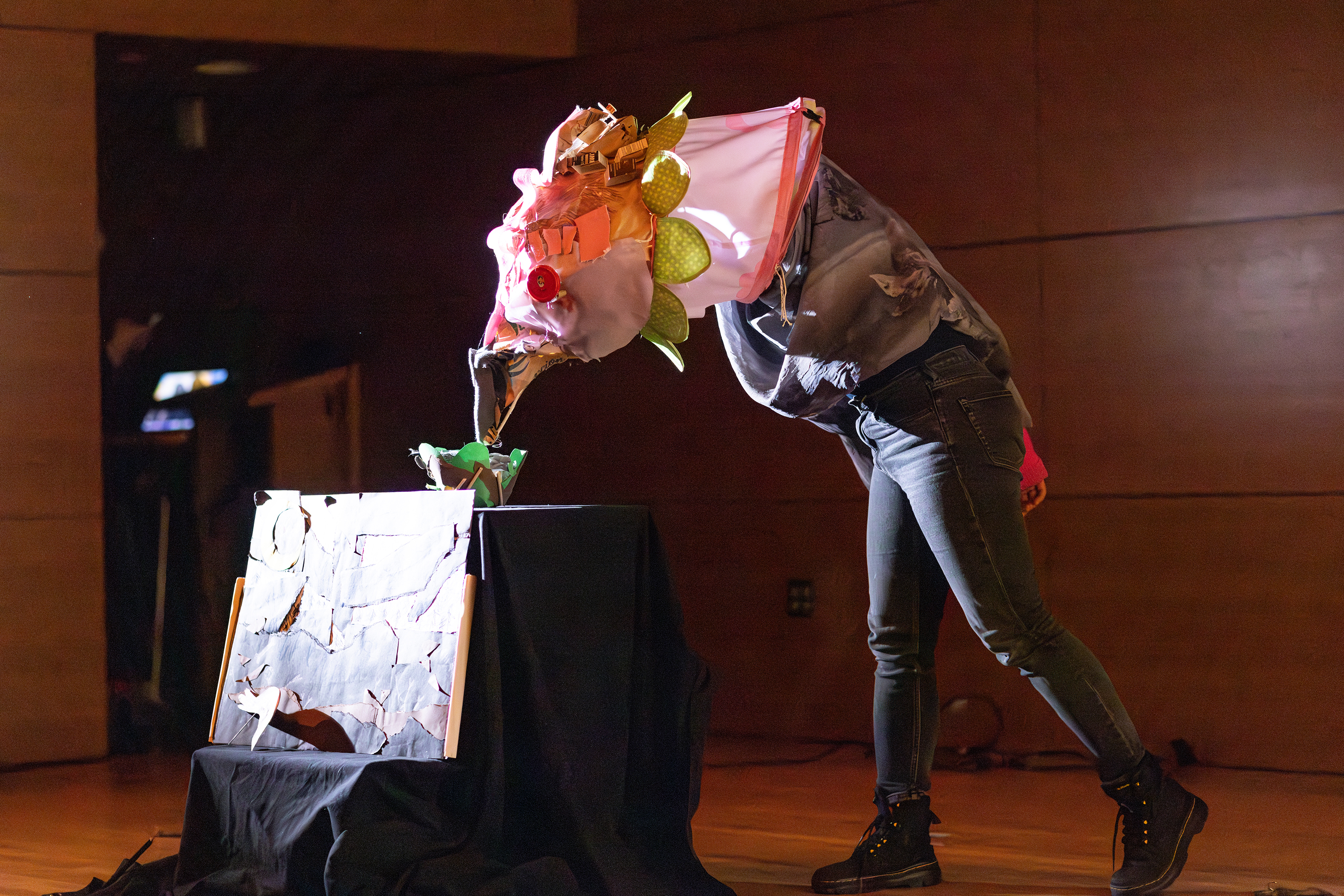 a student wearing a puppet head of a chicken performs on stage