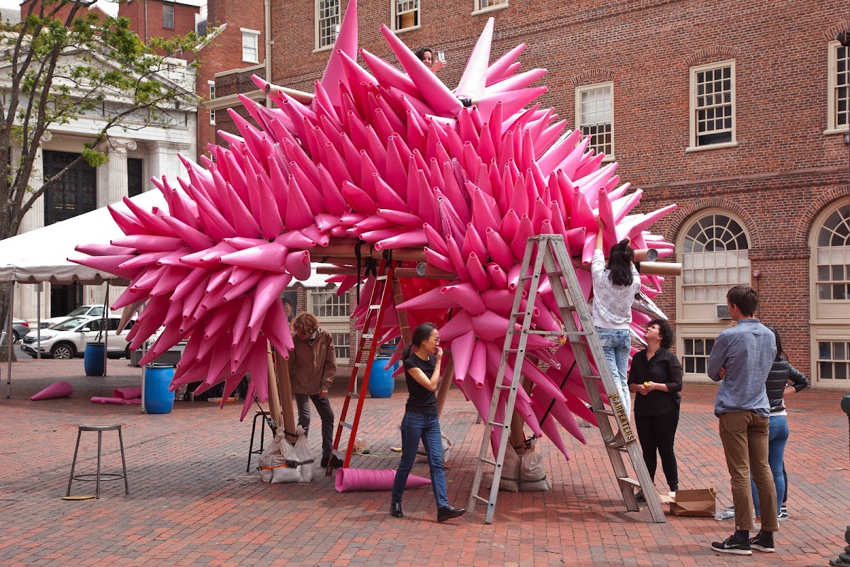 Students assembling a large, pink, multi-coned structure in Market Square