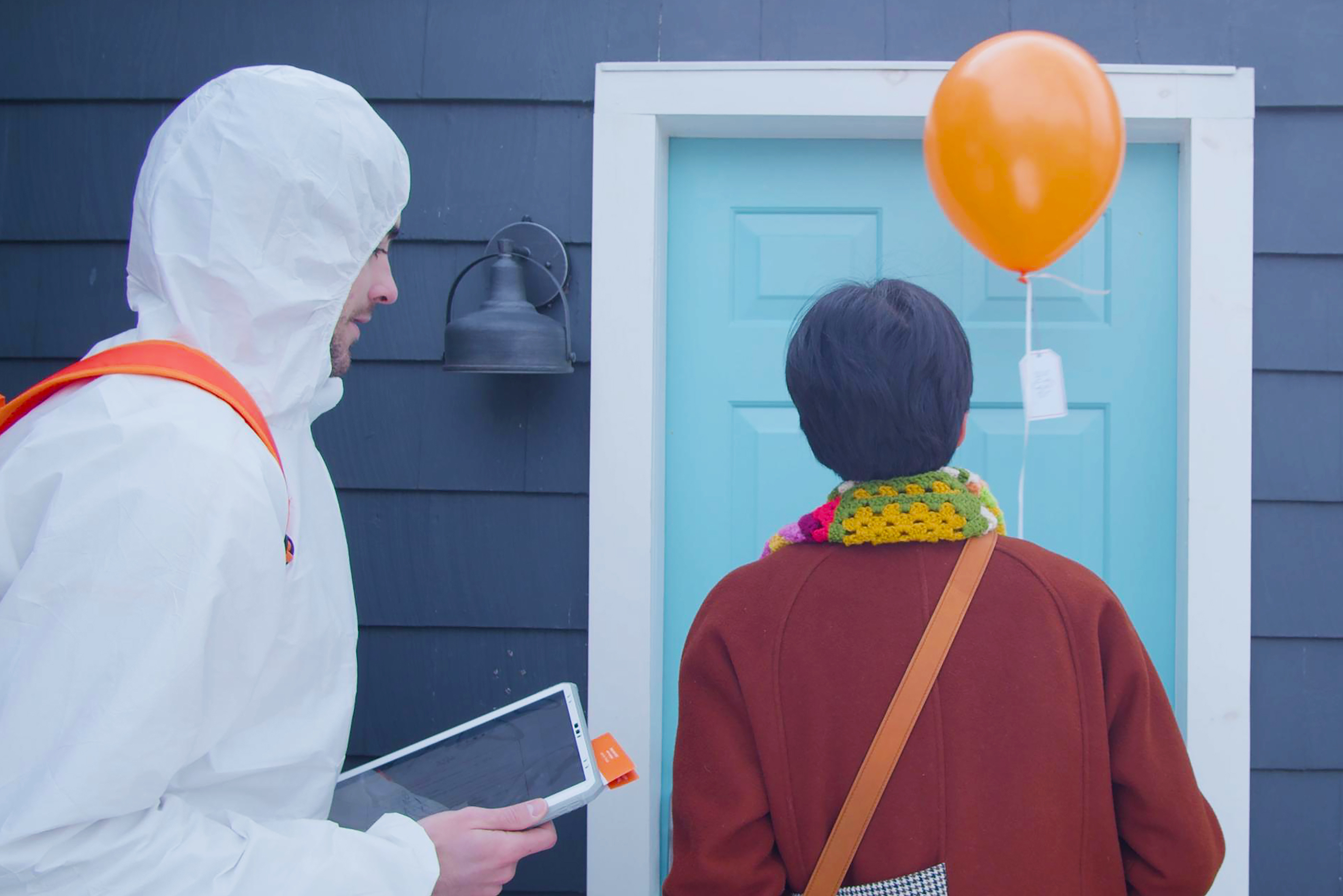 a woman with an orange balloon stands at the doorway