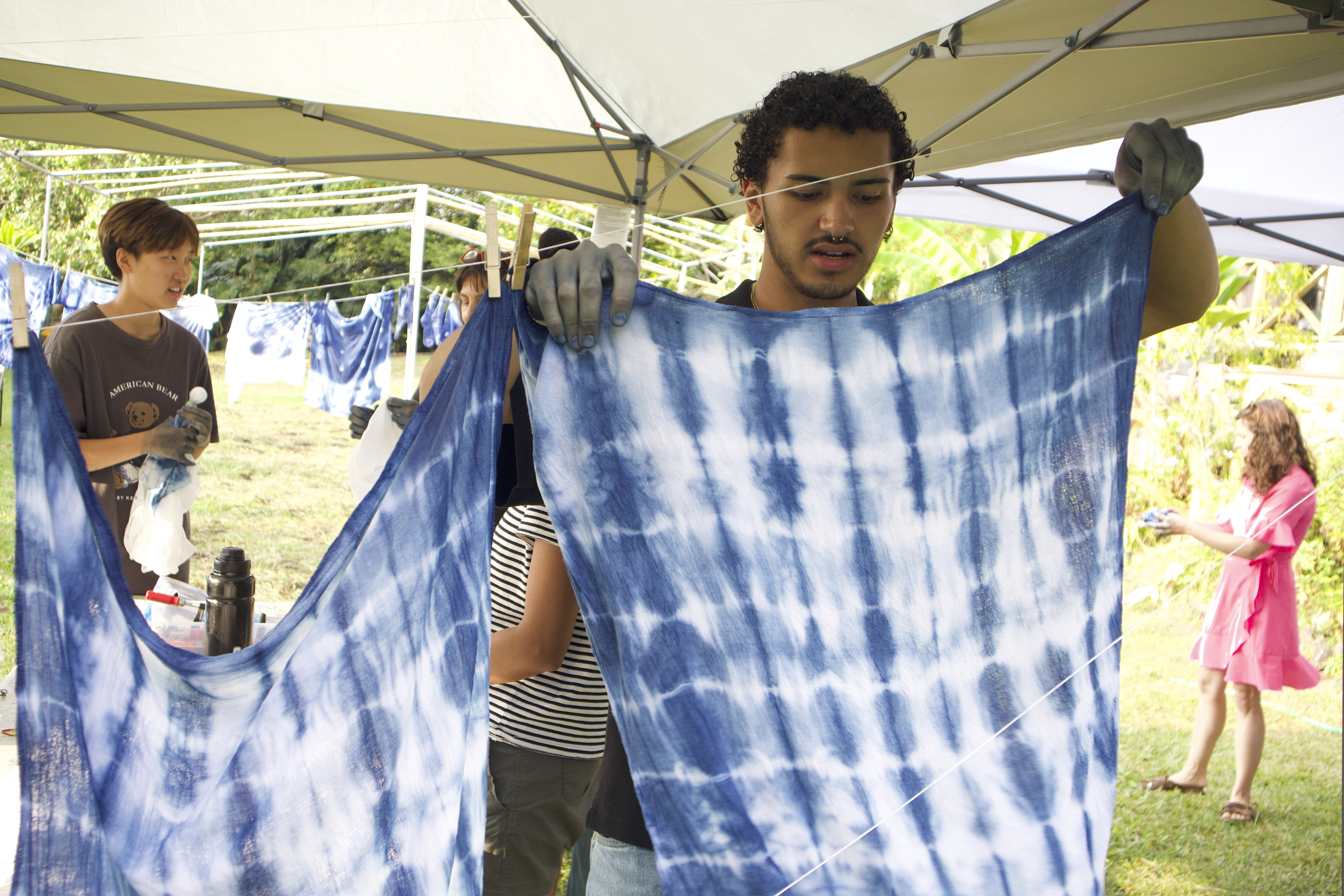 a student hangs a dyed textile to dry