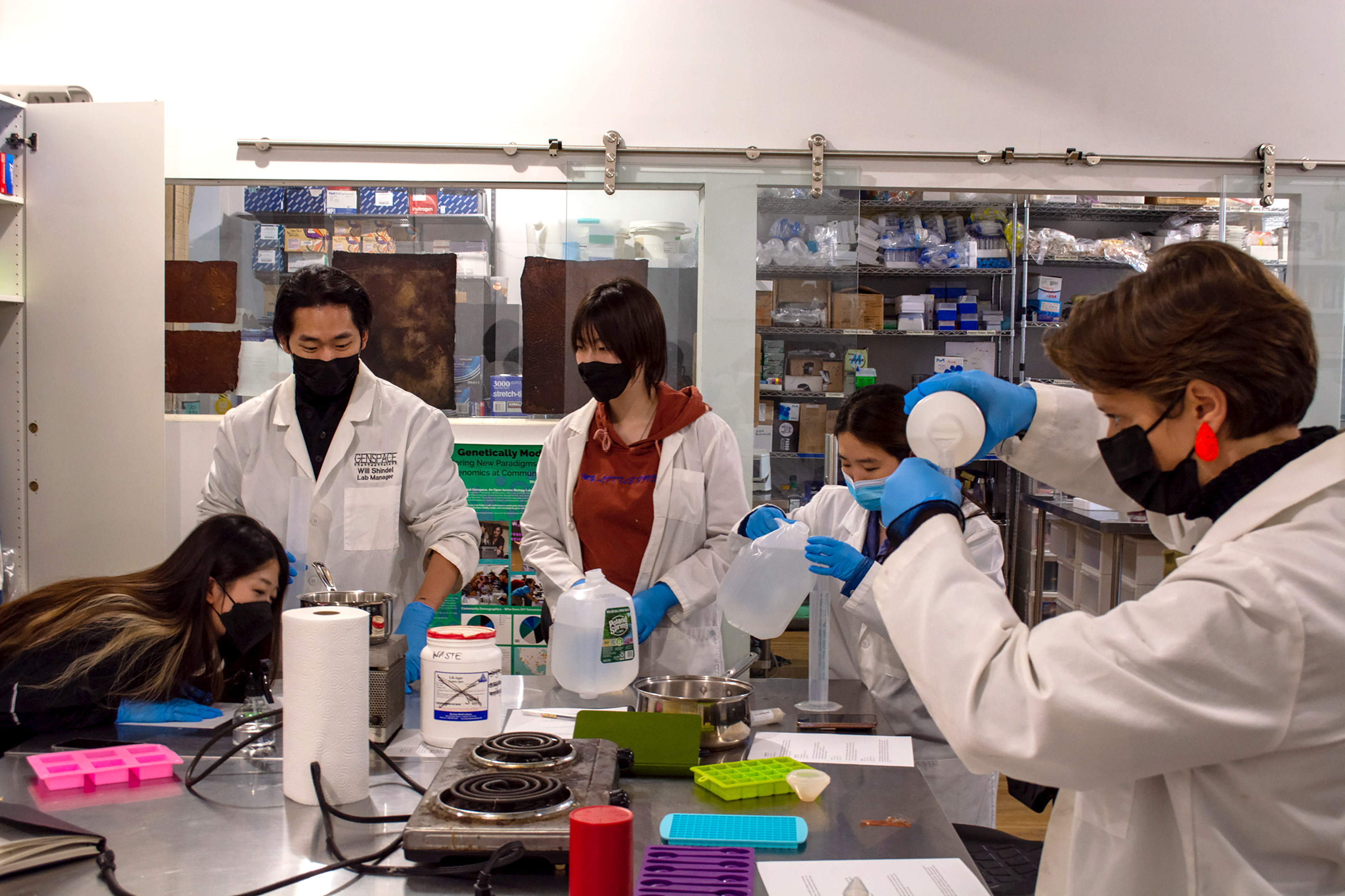 students gather around a lab table to experiment with "cooking" biomaterials on hot plates