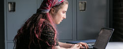 Student with scarf on head looking at computer.