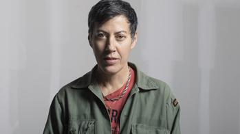Photograph of Nicole Eisenman in a khaki jacket and red t shirt.
