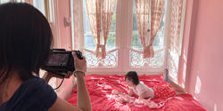a student films another student on the bed in a very pink room
