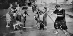 black-and-white image of kids playing in the spray from a fire hydrant