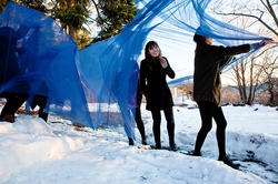 Students installing blue fabric sculpture outdoors in snow