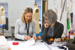 a RISD student and faculty member talk at a workstation inside the Apparel Design studios