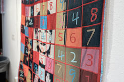 A quilt by Xiao Guo featuring a sudoku grid overtop an image of her mother's face in bright colors