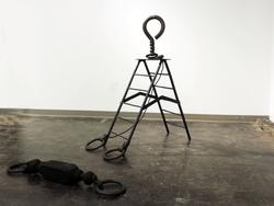 Student work by Odette Blaisdell BFA 2018. A metal ladder with large hooks and rings attached at the base and top.