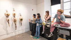 juniors in the Printmaking department discuss a wall hanging that looks like giant seed pods