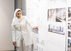 a students points out a detail in her wall-mounted design rendering