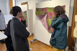 Em Kapp presents two quilts to the class featuring a grassy green background with pink squares and little horses woven overtop
