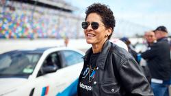 Artist Julie Mehretu on a race track with BMW sports cars in the background.