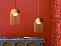 Two lamps with metal fringe against a red wall.