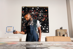 Artist Tavares Strachan holding a bottle of ink in a studio.