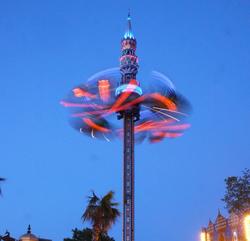 Image of an amusement park ride lit up at night in pink and blue colors.
