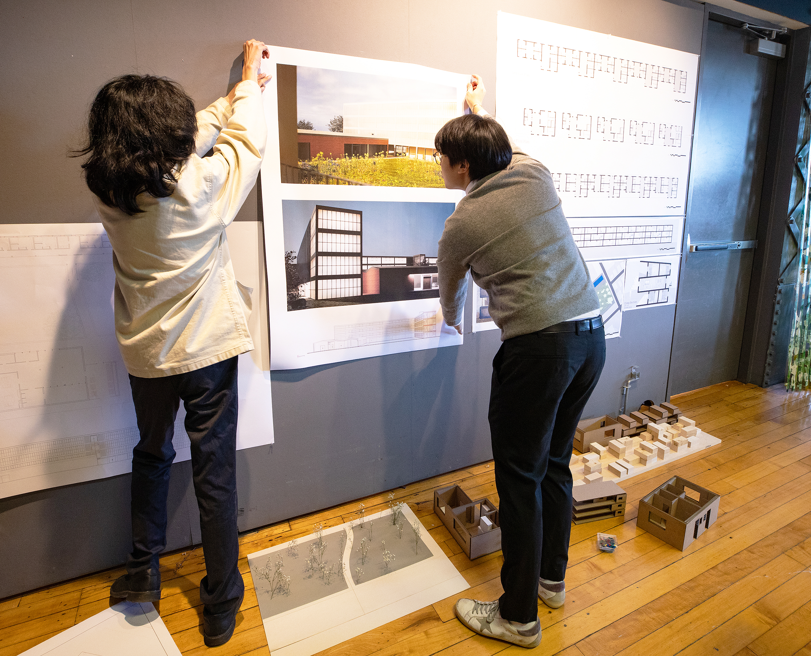 students pin up renderings in preparation for final crits