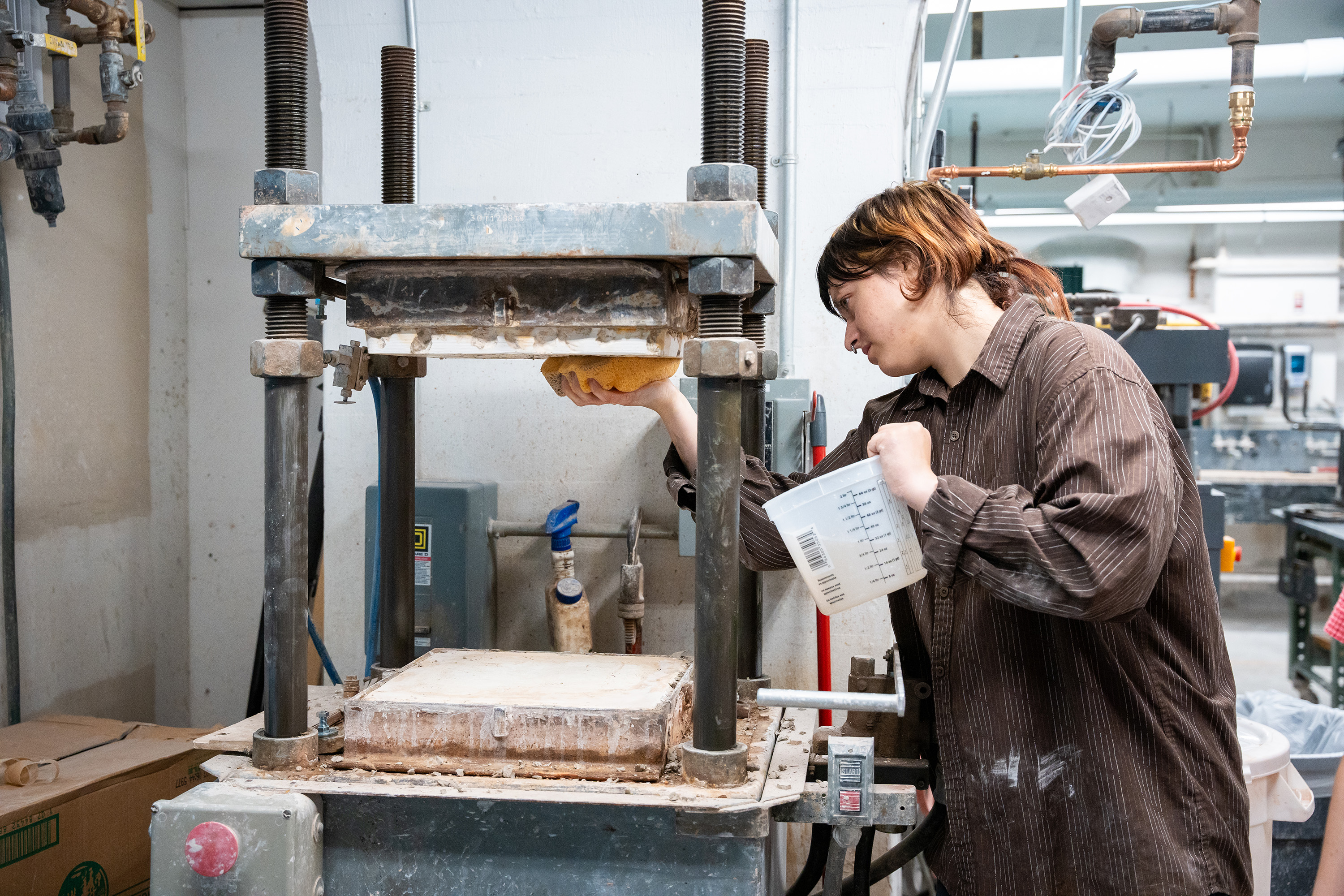 a student cleans the die inside the RAM press