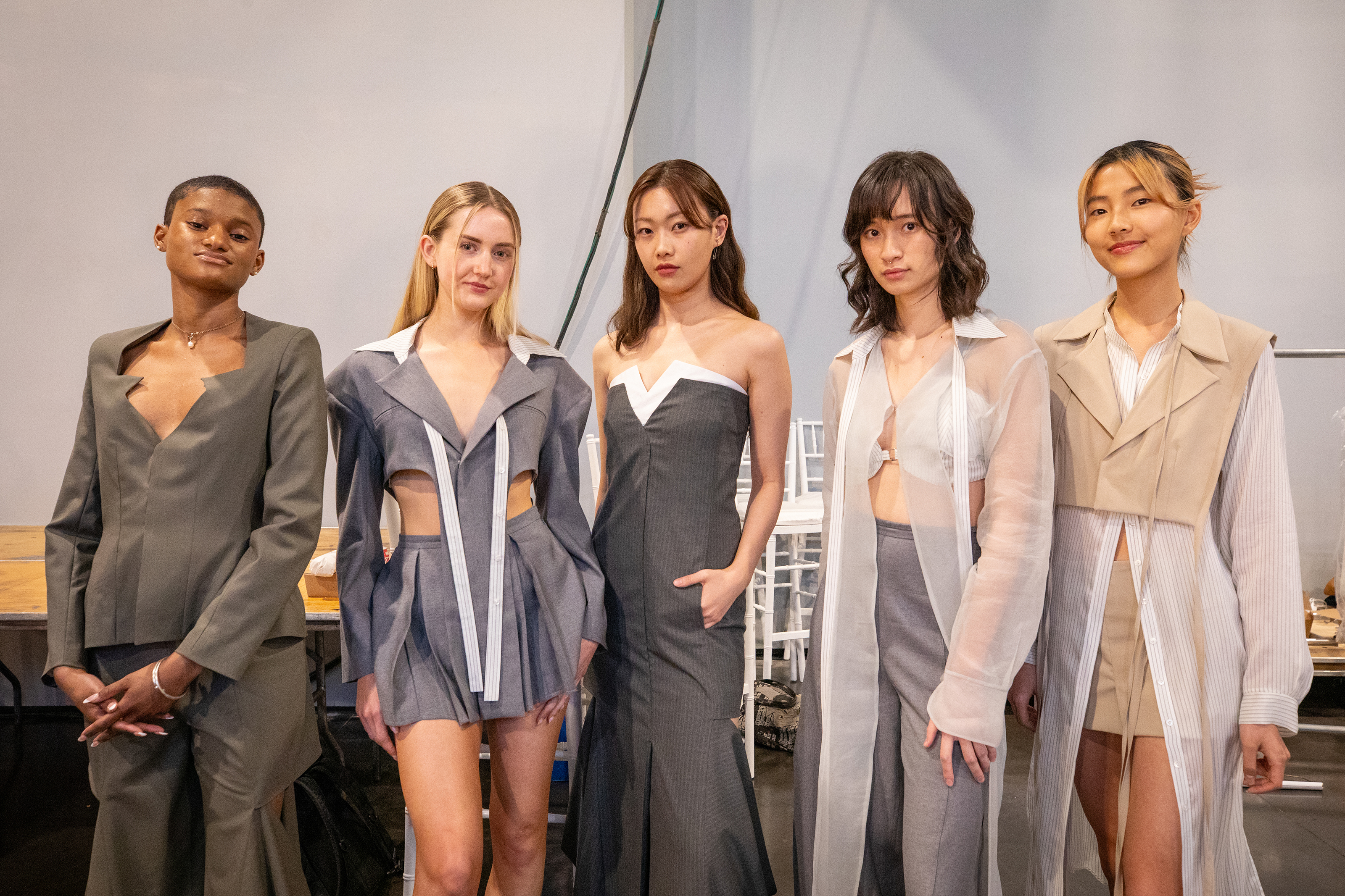 models line up backstage in looks combining sheers and business suits