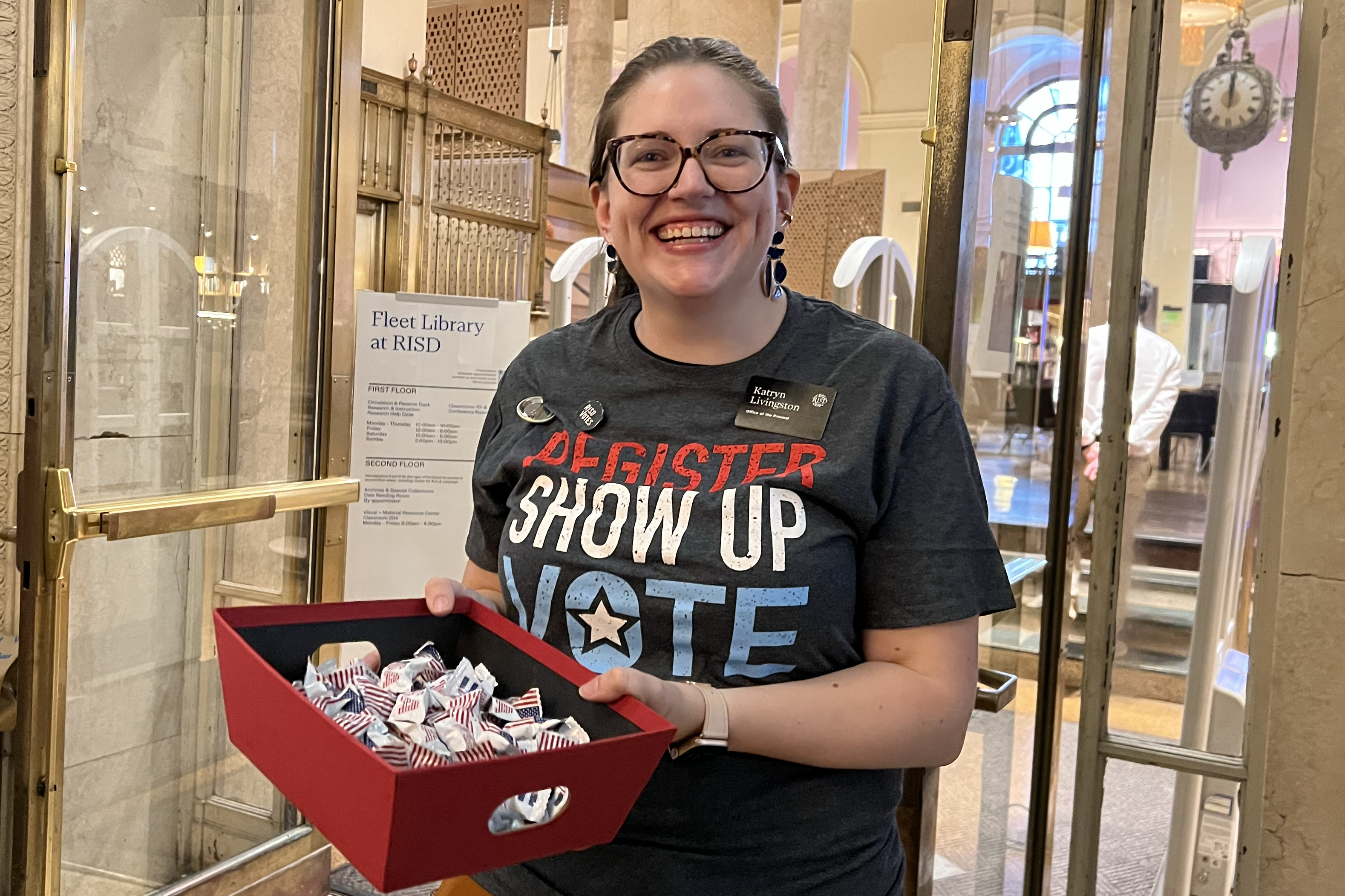 staff member Katryn Livingston hands out US flag candies and welcomes participants