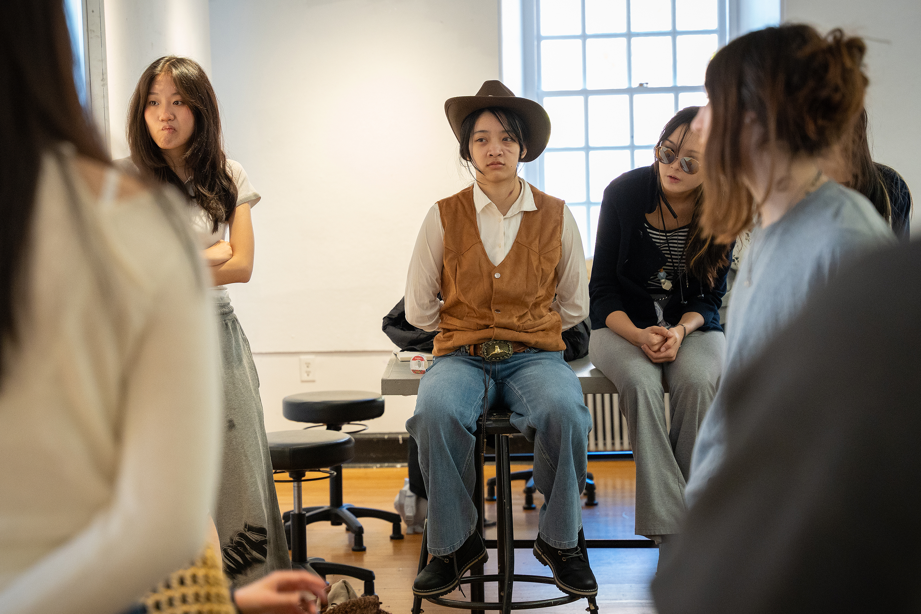 students, including one dressed as a cowgirl, gather for a crit of cowboy culture projects