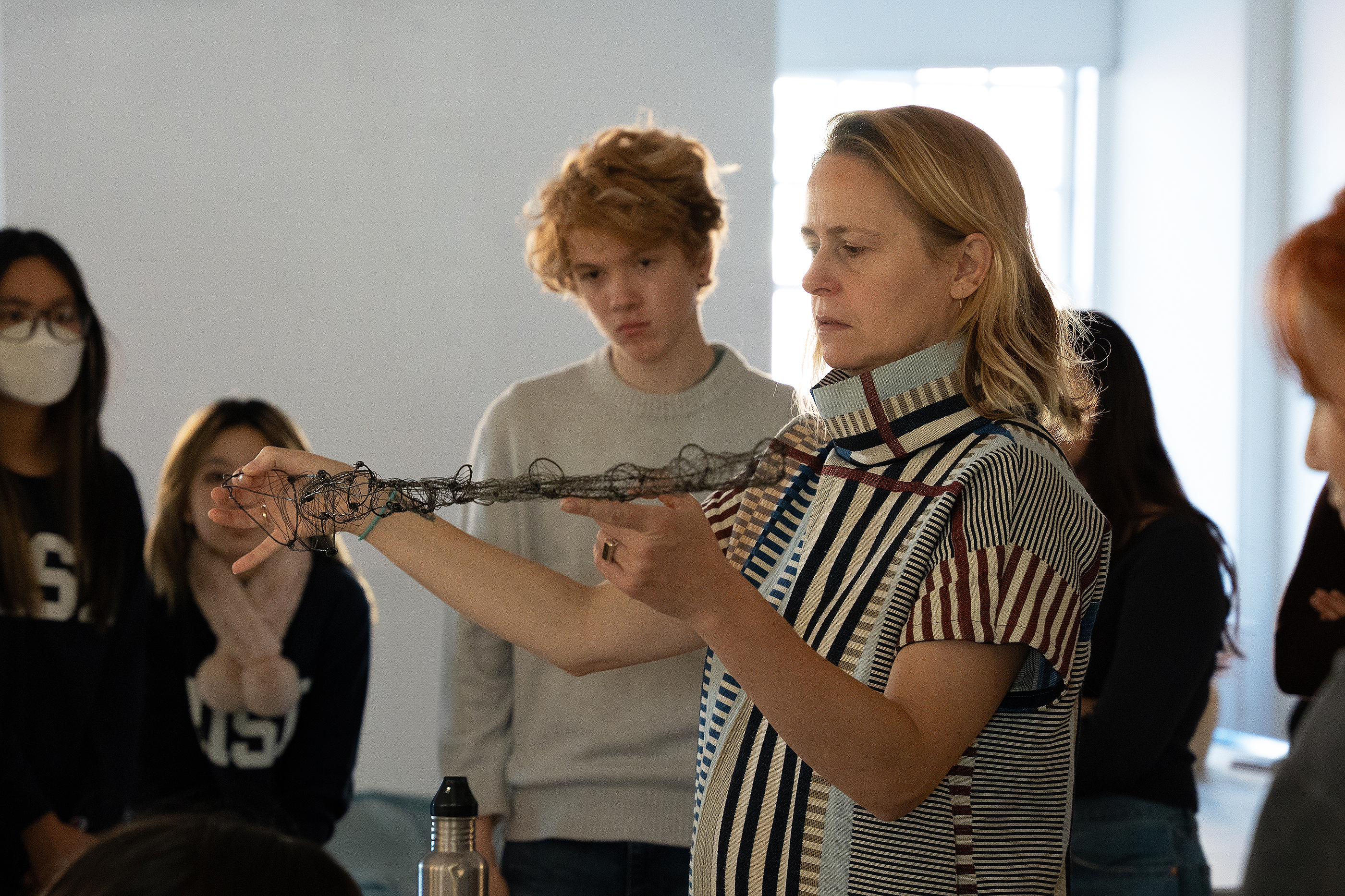 Mimi Cabell examines a wire object as students look on