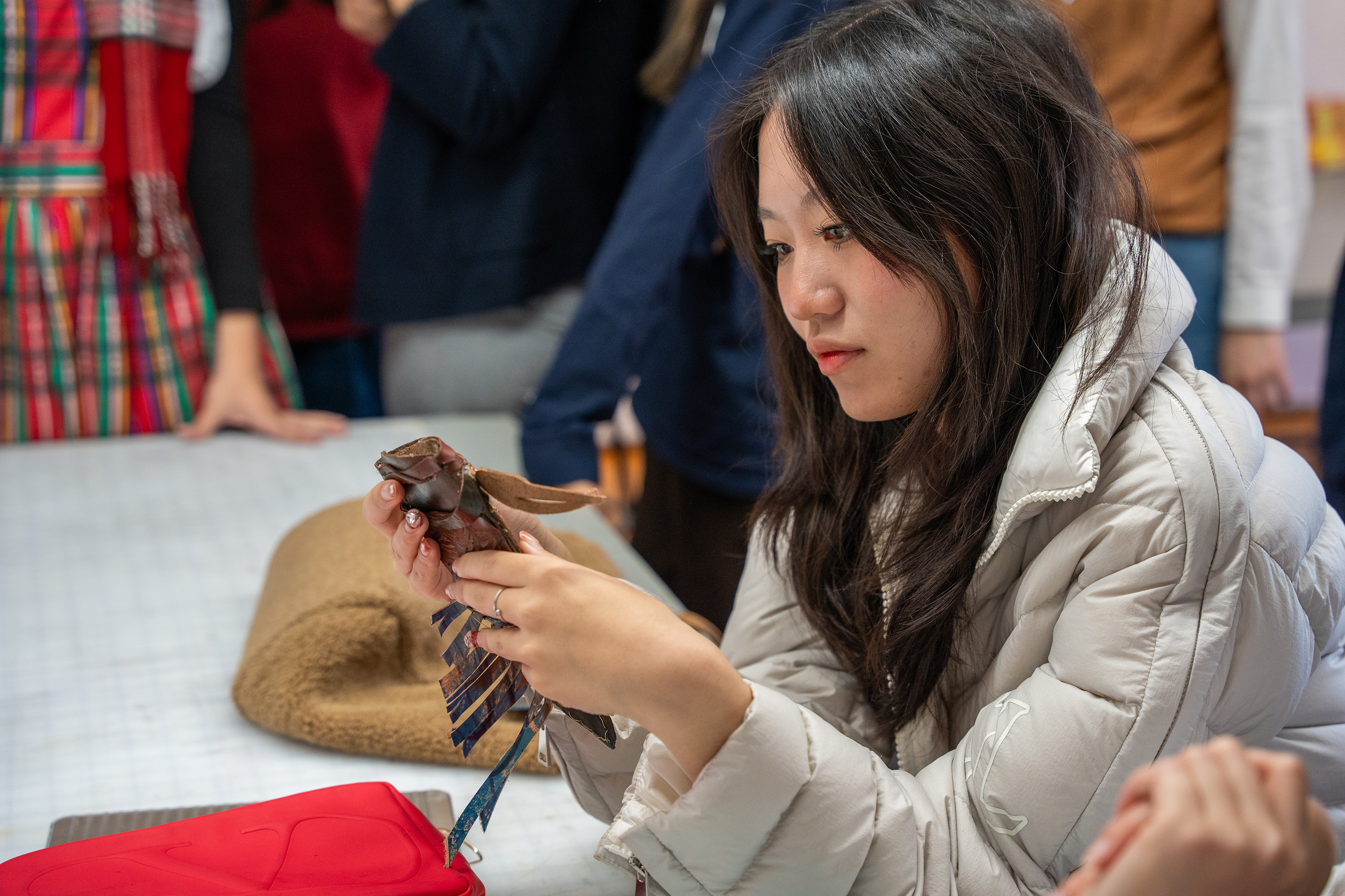 a student gazes at a leather knife sheath created by a classmate