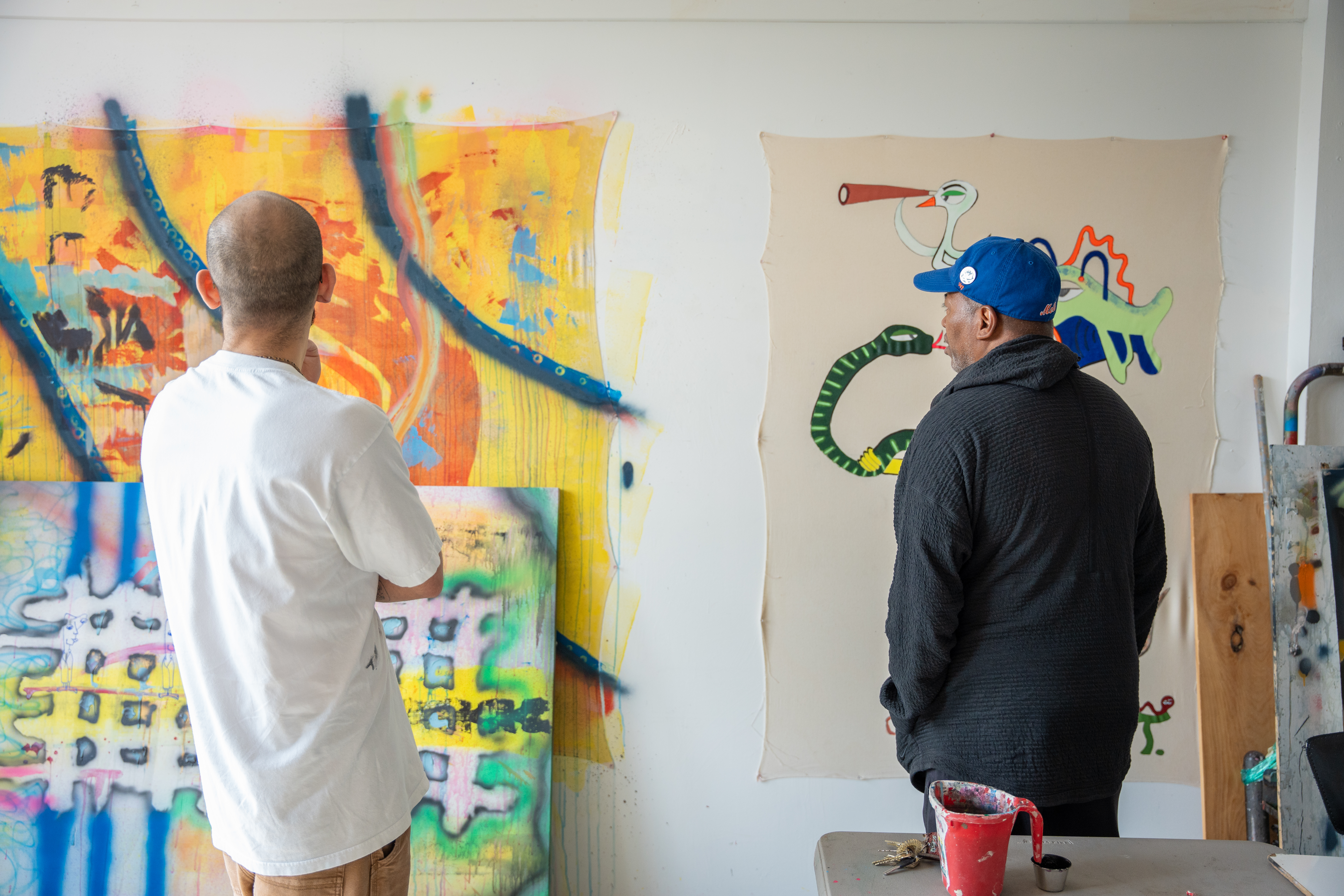 A RISD student and artist Cey Adams view colorful artwork hung on a wall