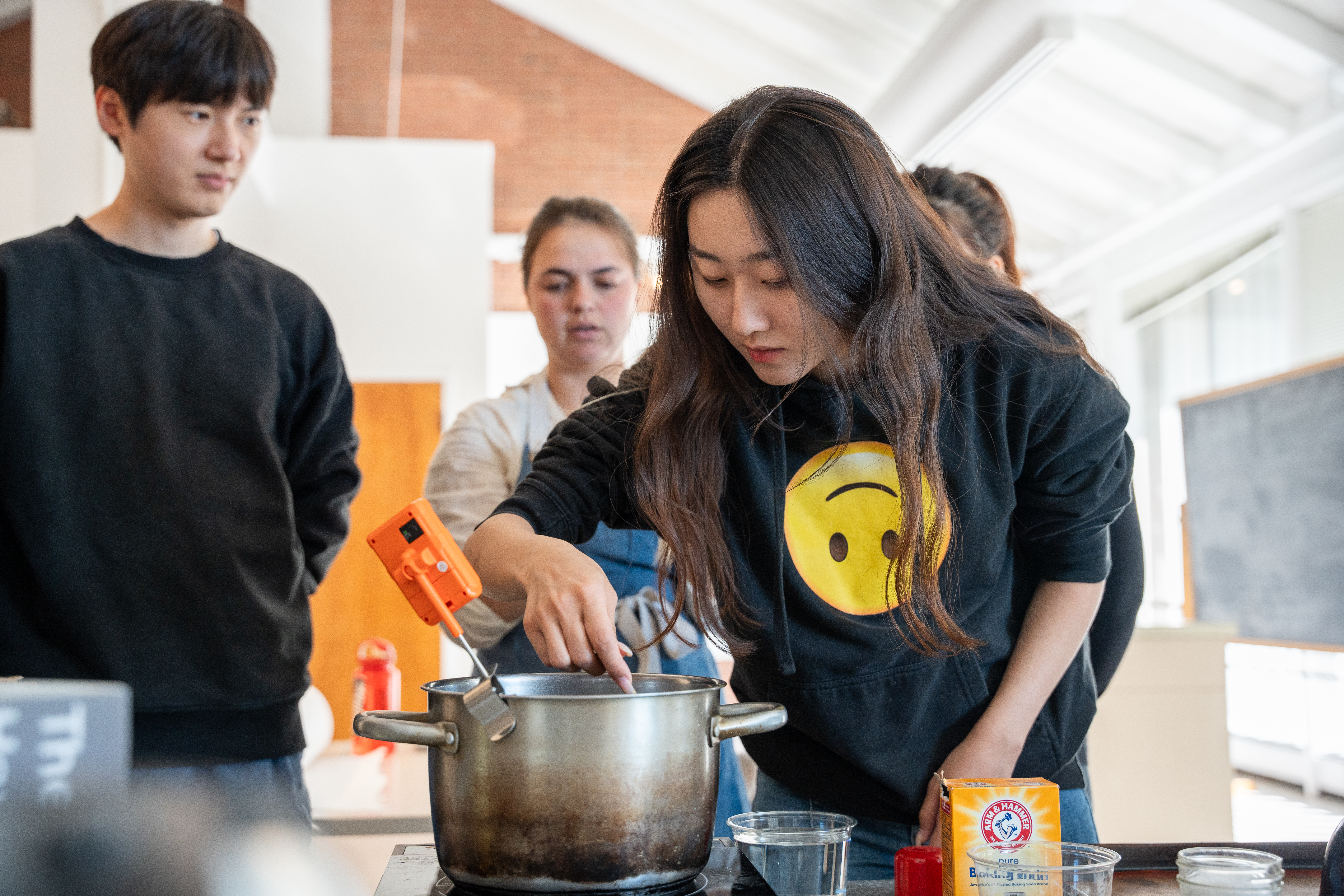 A student brushes sugar crystals inside of a steel pot