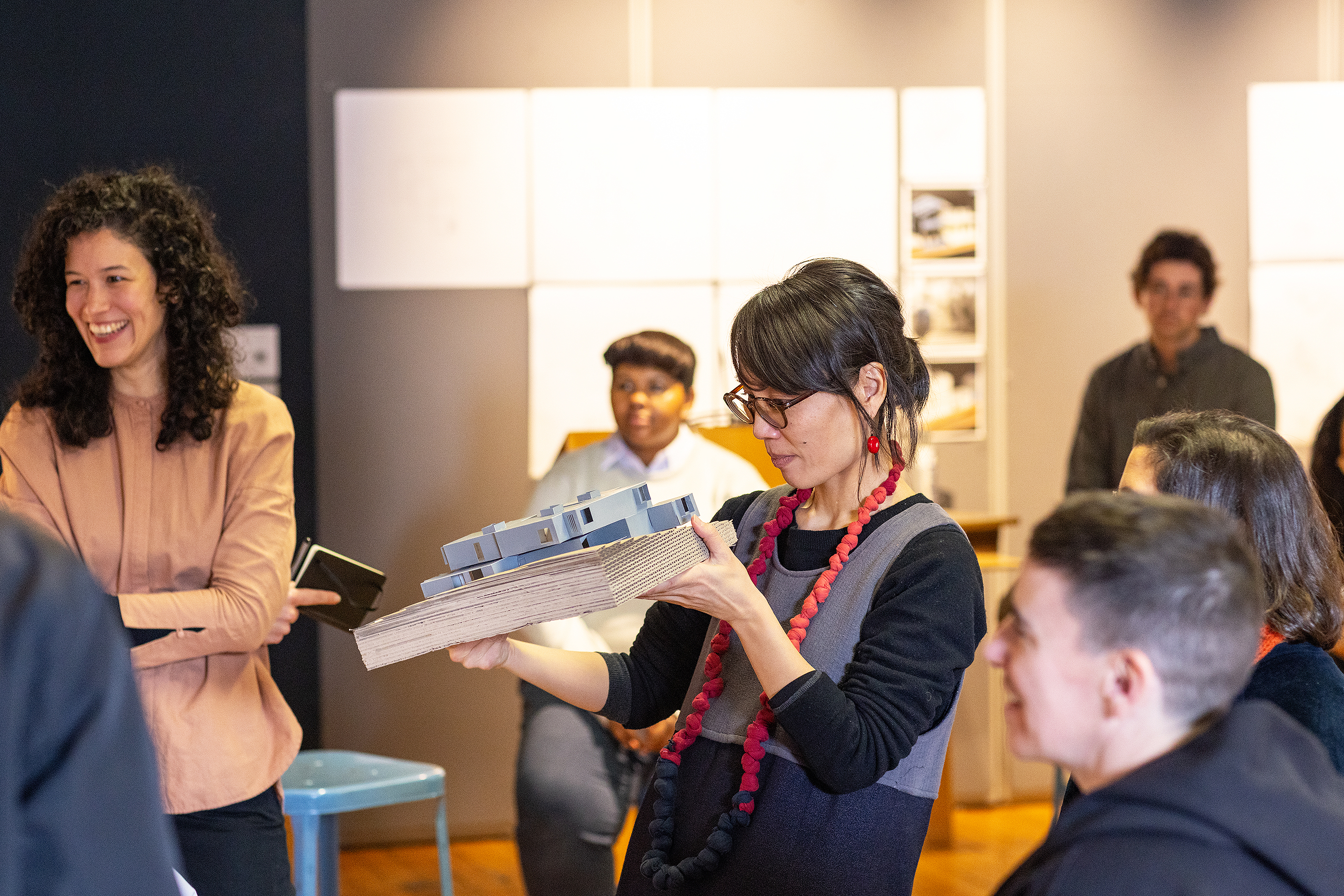 a visiting critic holds an architectural model to get a better look
