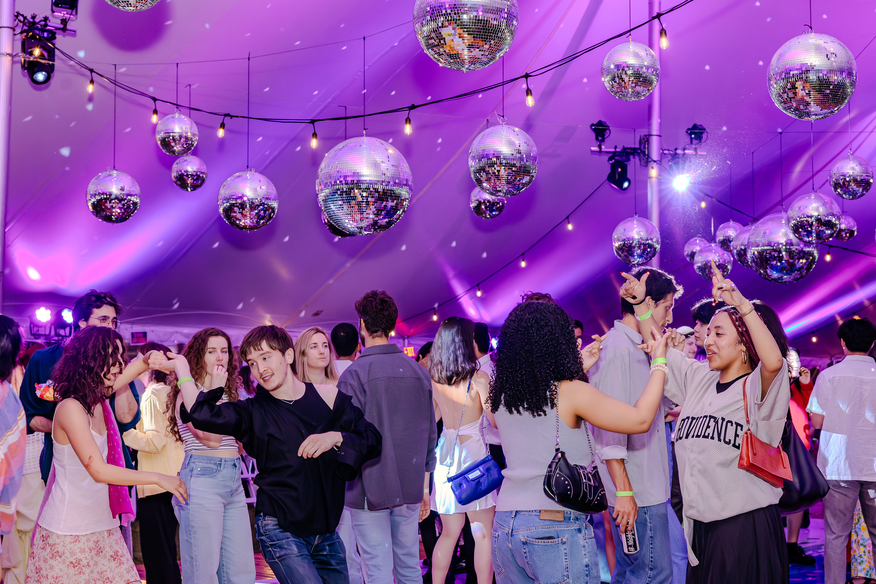 alums dancing under purple lights at Commencement + Reunion Weekend 2024