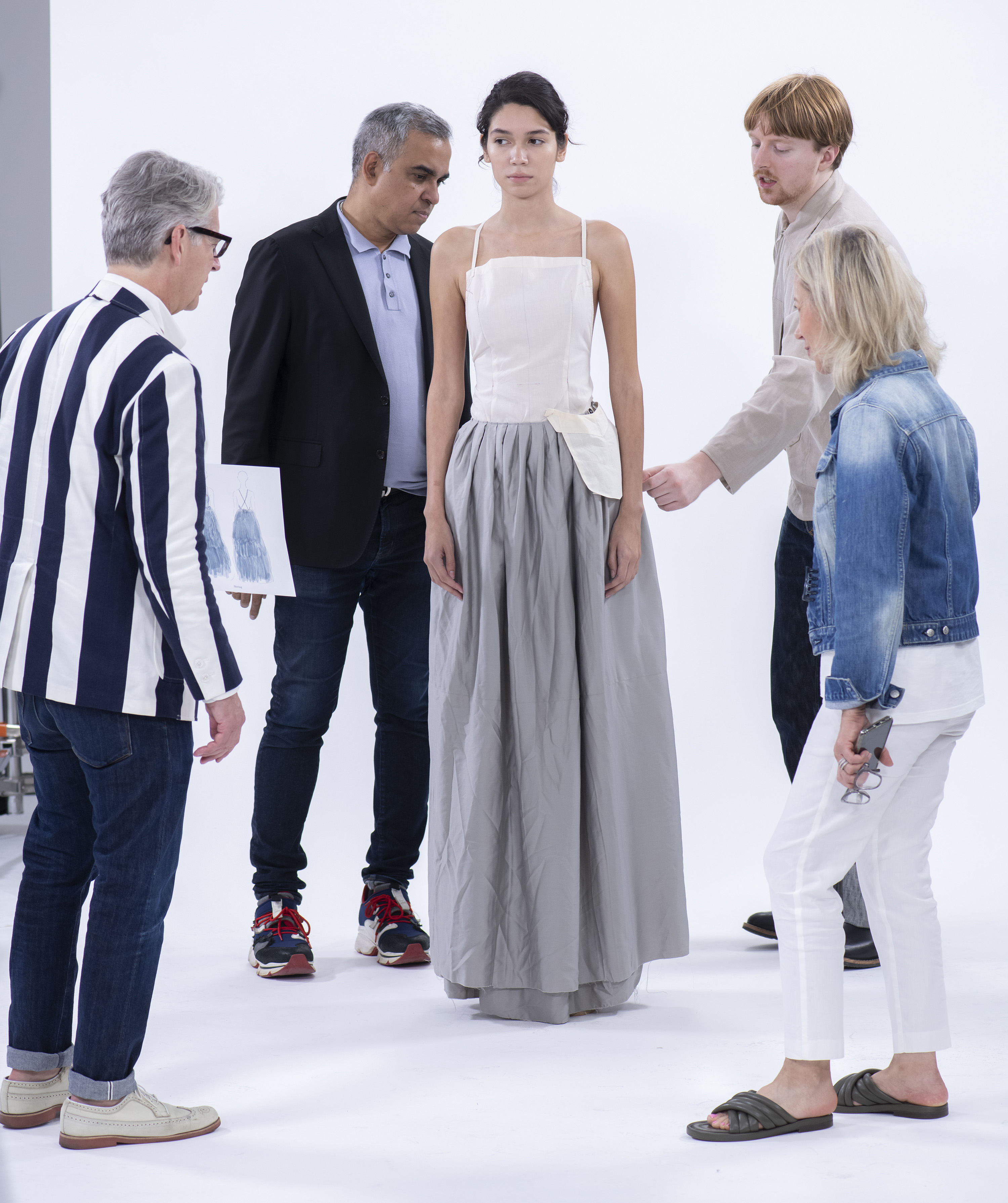 Hawk and competition mentors gather around a model at NYC fitting