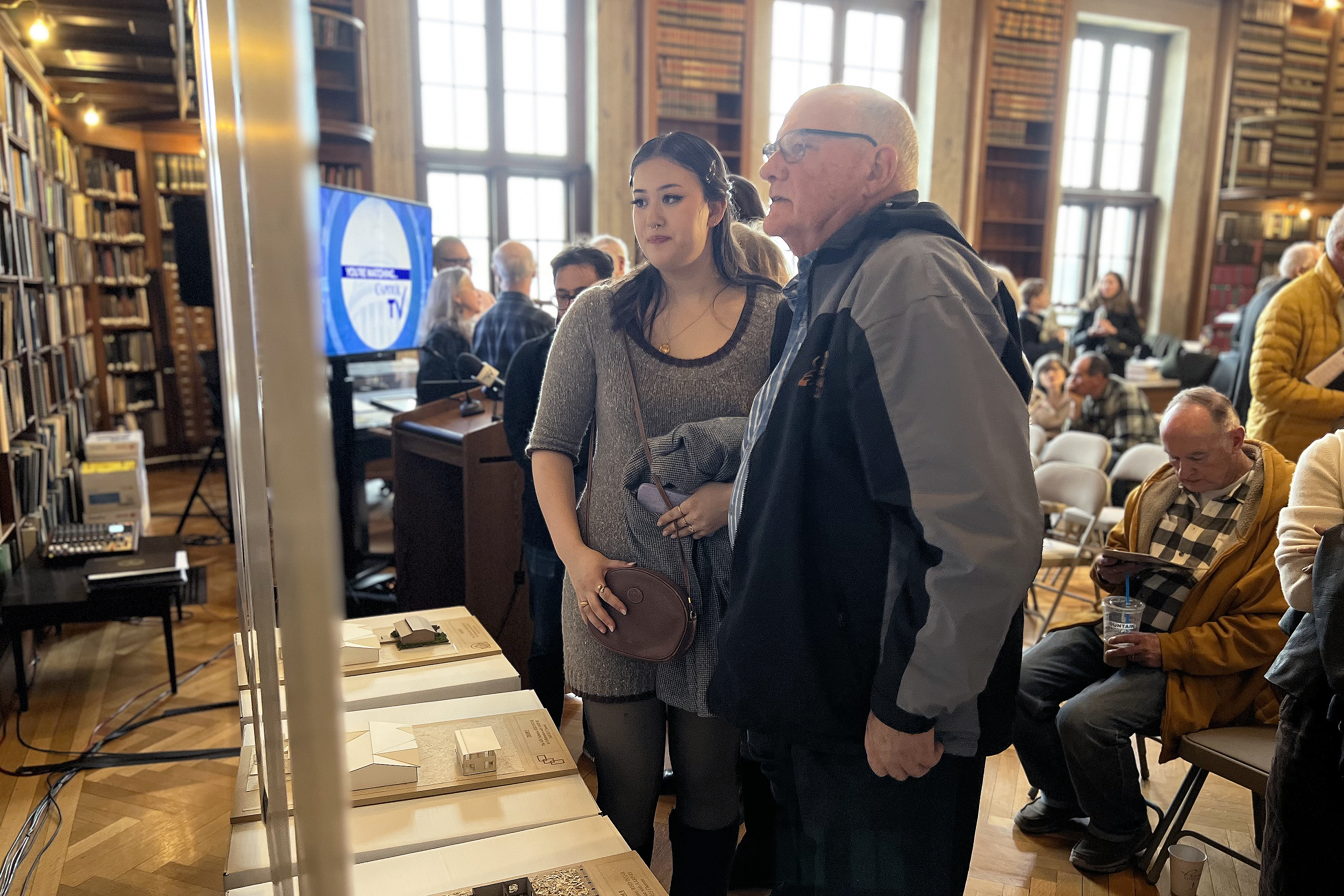 visitors check out student ADU designs in the State House library