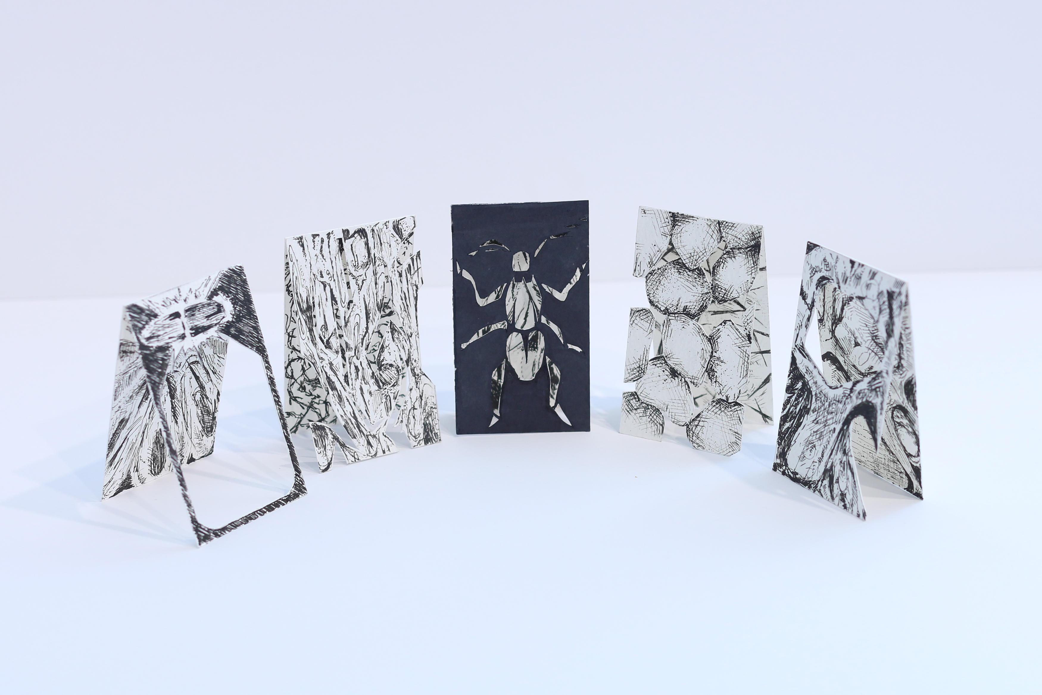 four cut-paper artworks in black and white