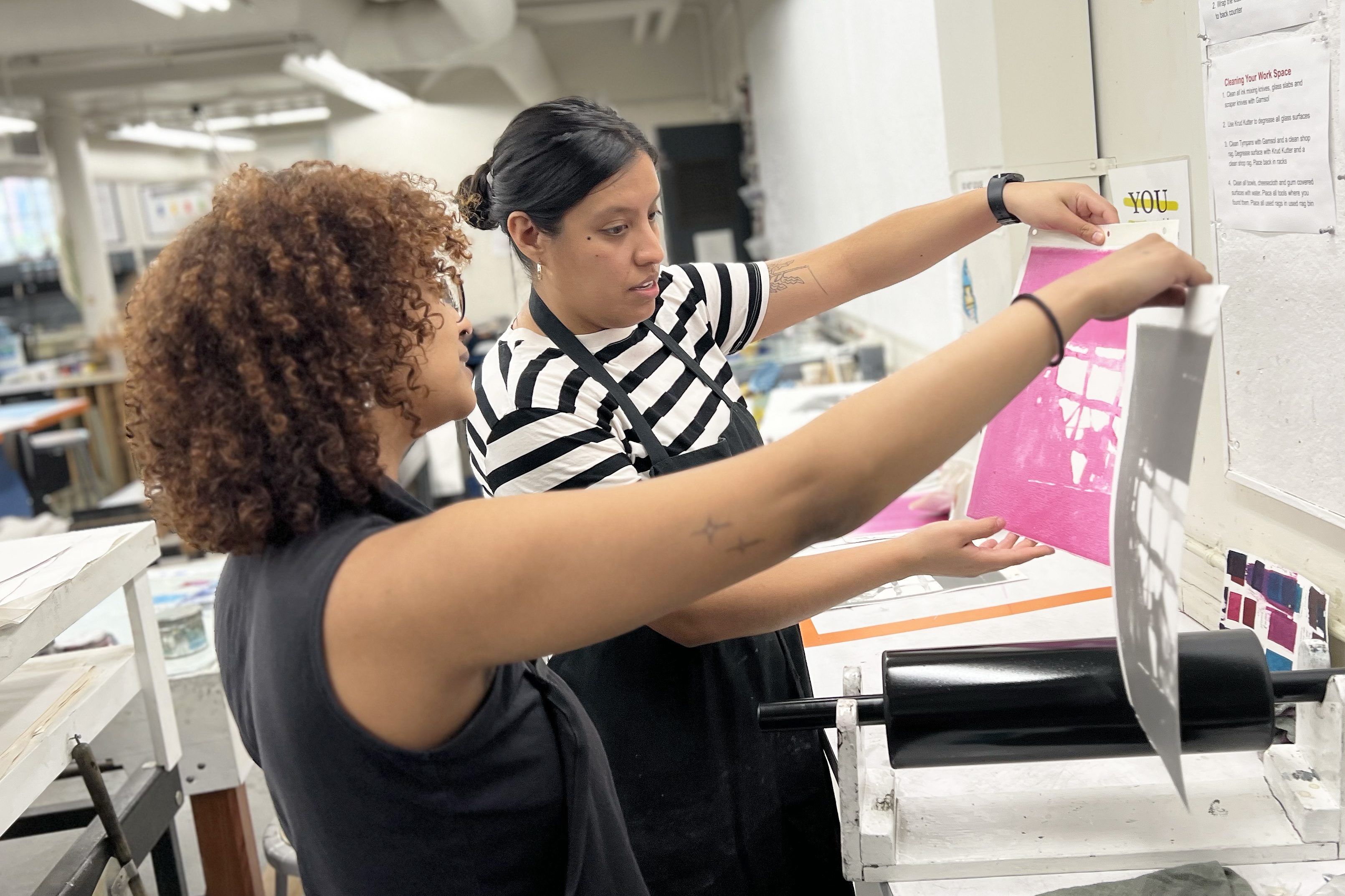 a student and Estrada Hernandez hold up prints in progress