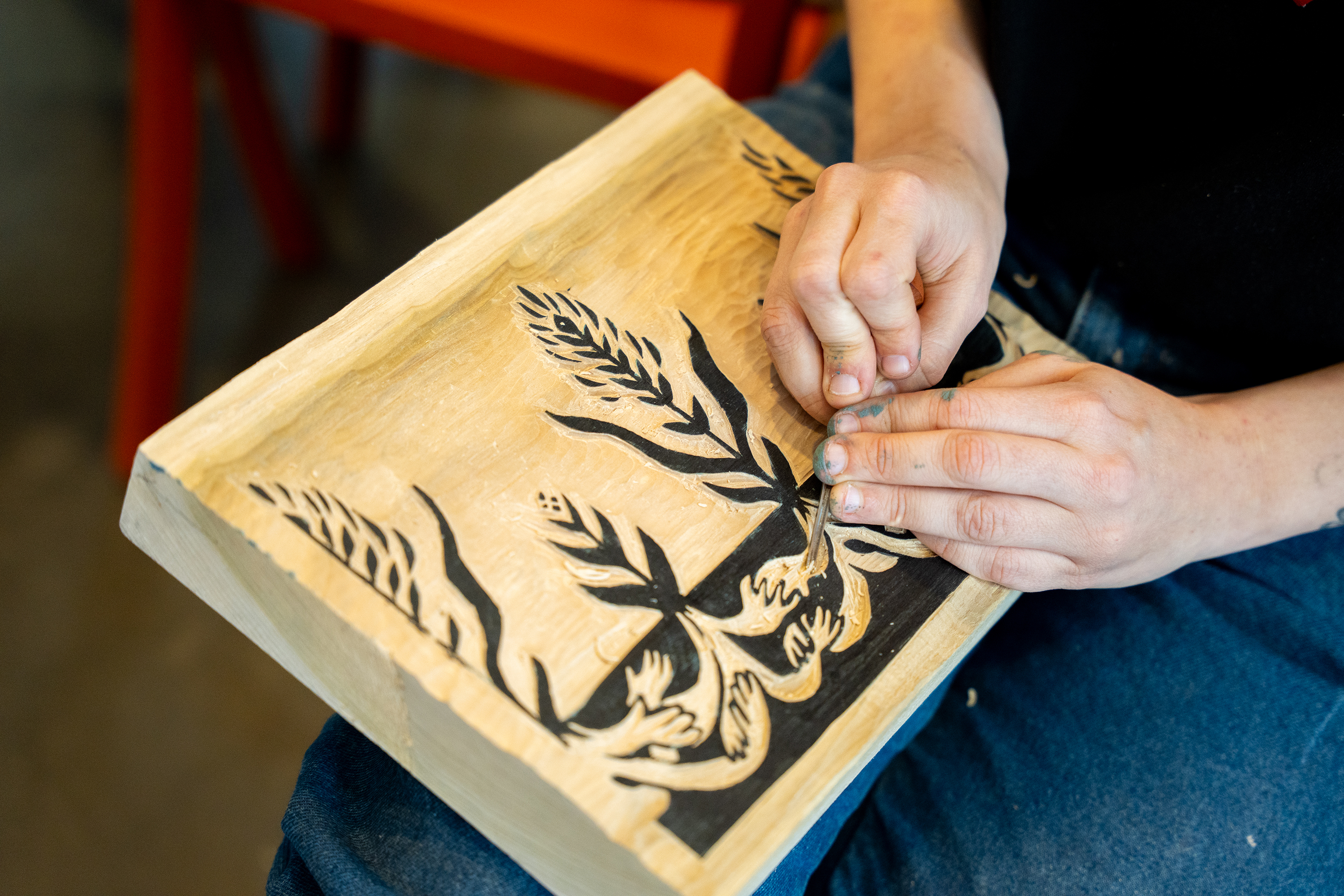 a student carving their design into a block of poplar