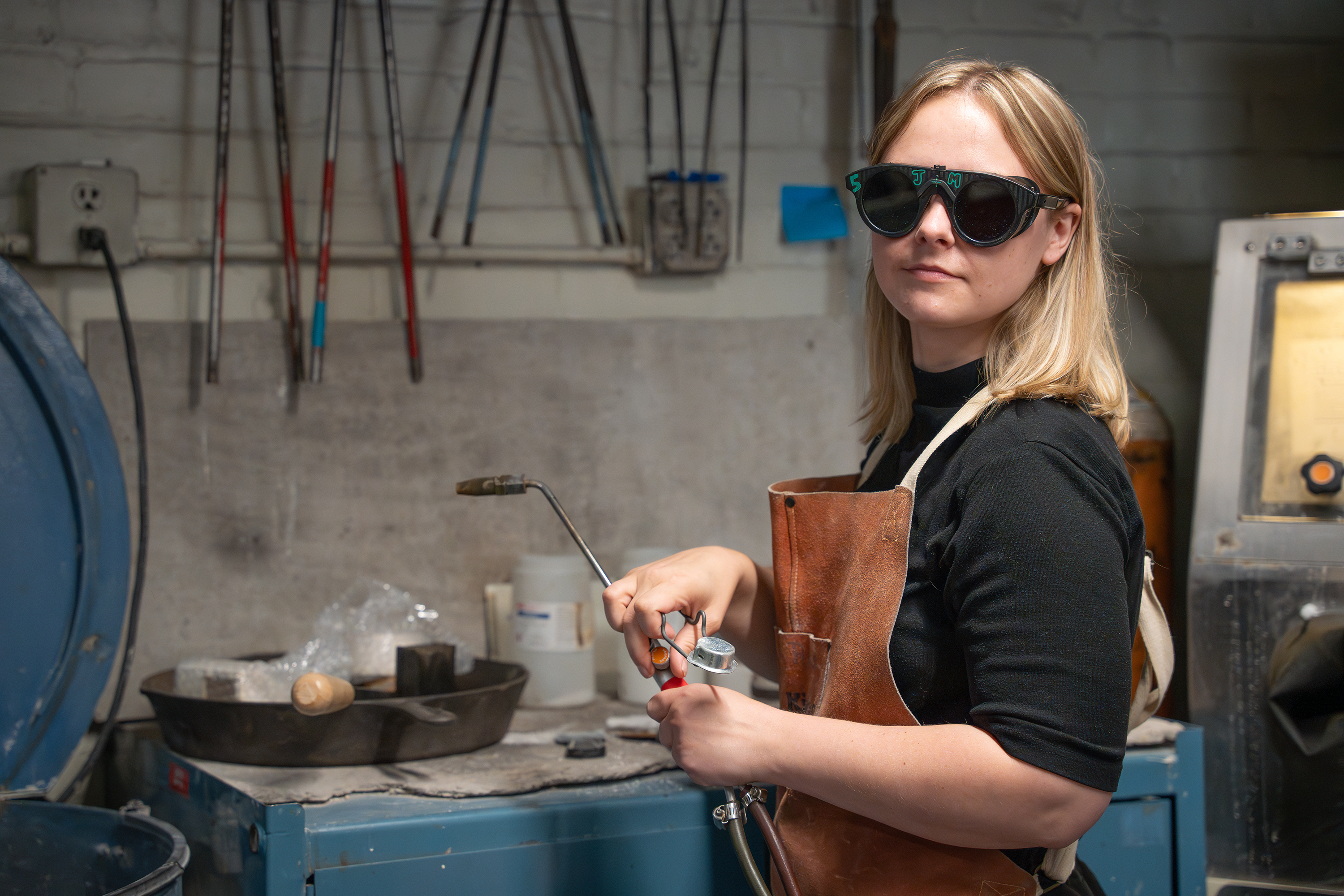 an apprentice-in-training wearing blackout goggles prepares to light a natural gas torch