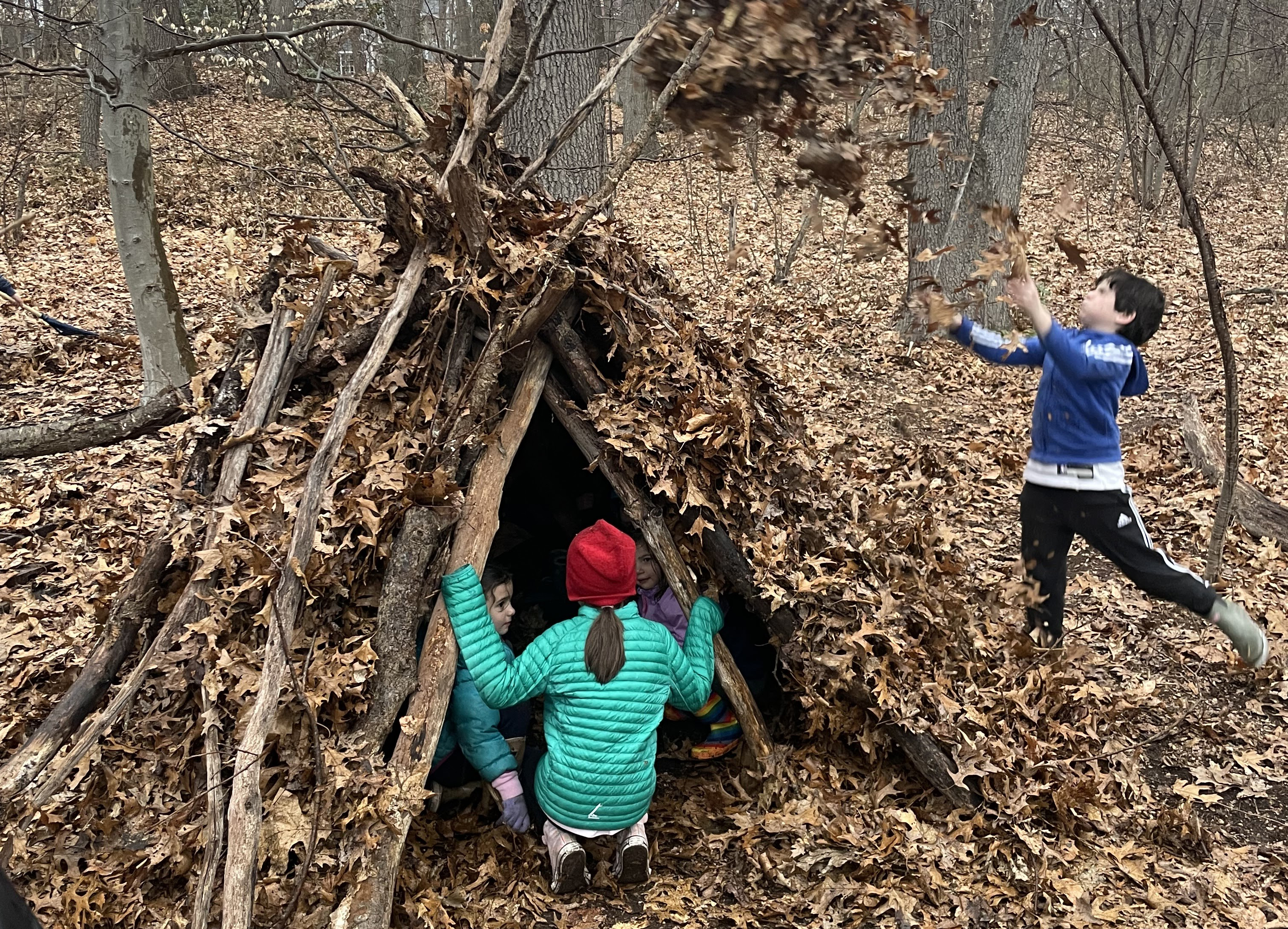 kids build an outdoor fort using fallen branches and dried leaves