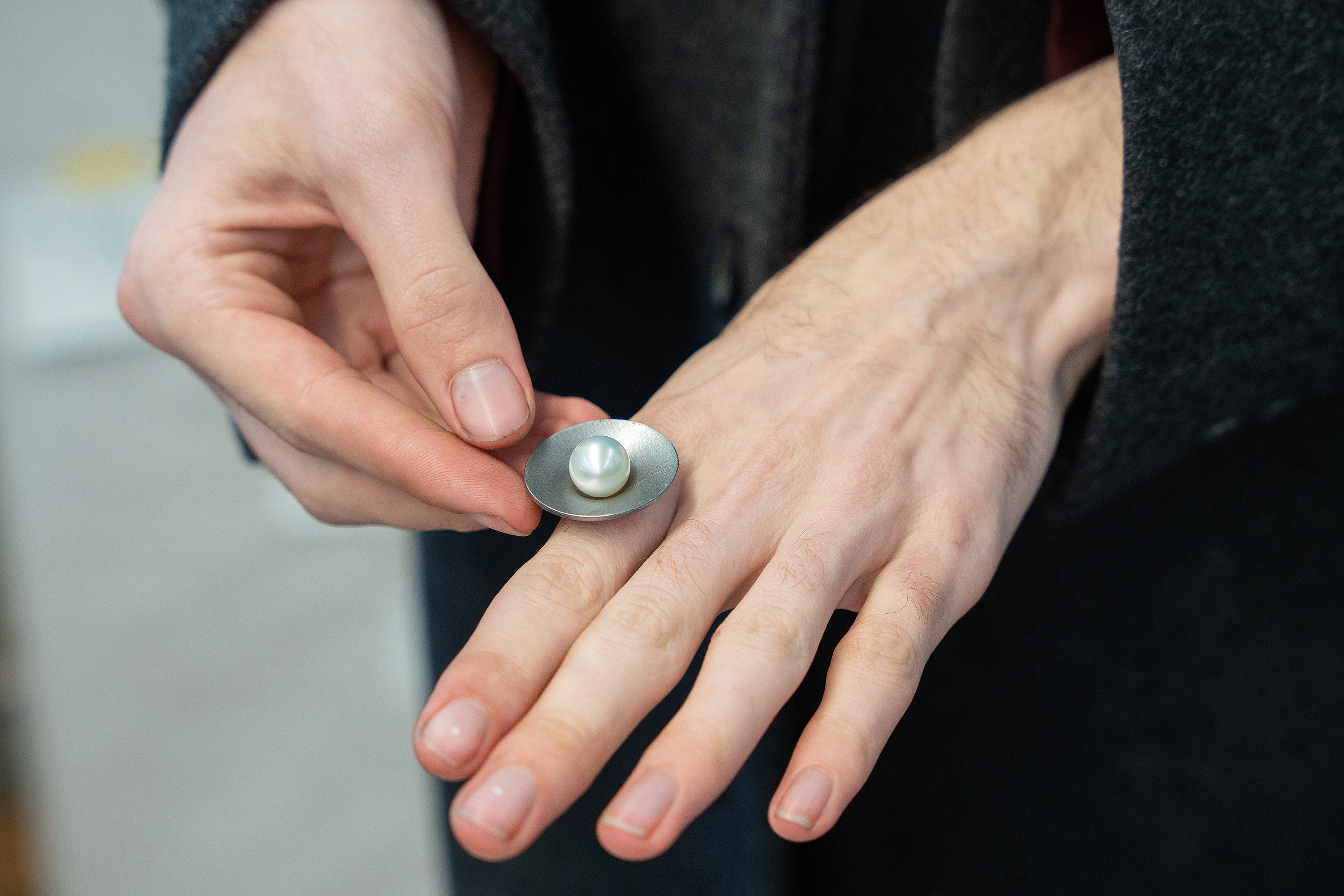 a student shows how the setting she is creating will work with a large pearl