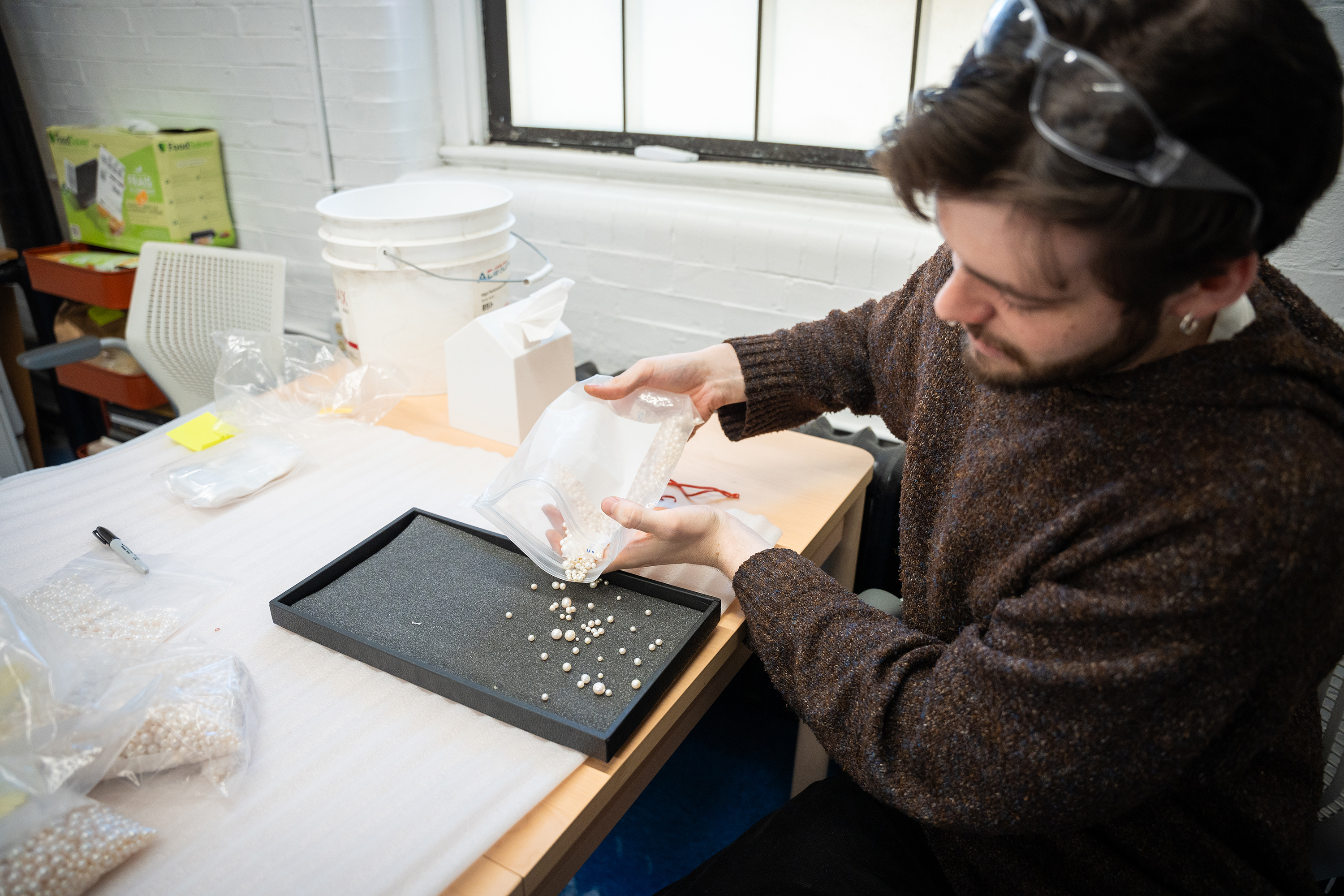 a student pours pearls onto a tray for sorting and selecting