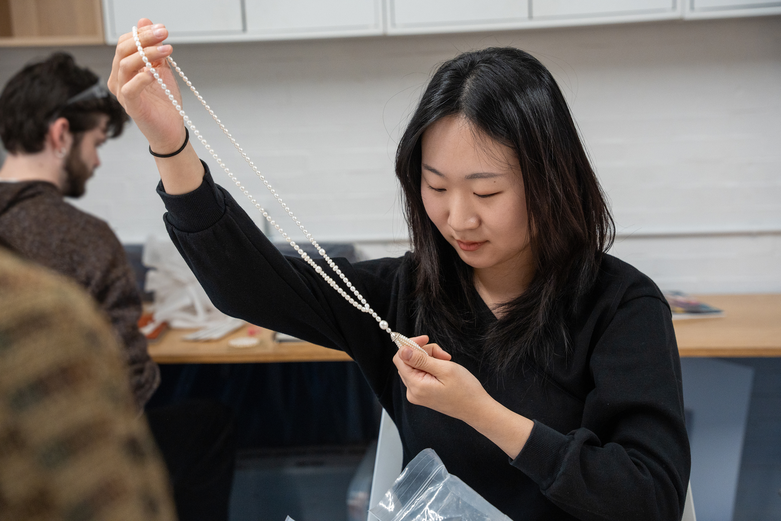 a student admires a string of pearls in the lab