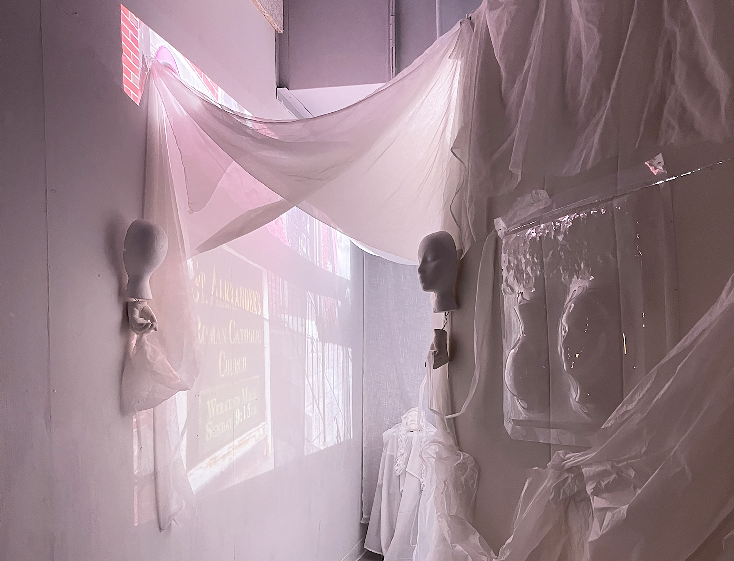 image of completed immersive installation featuring soft materials, human heads and projections