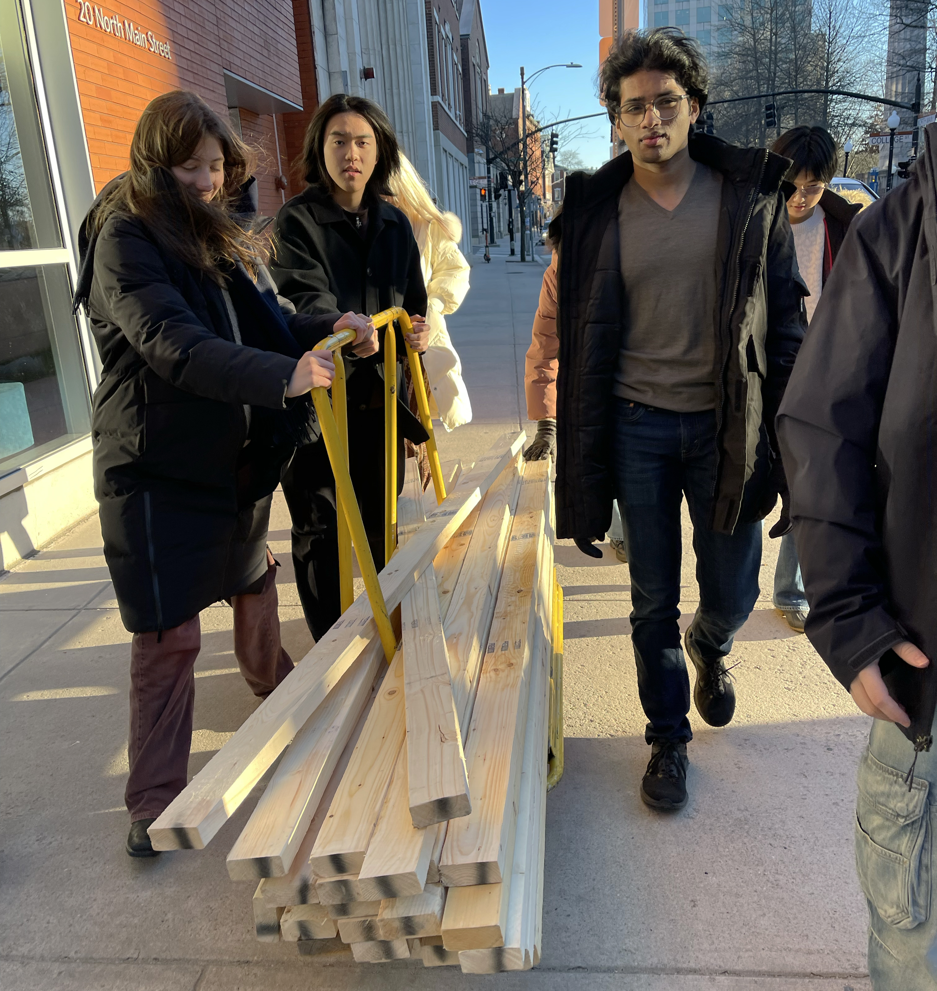 students use a dolly to move lumber down Main Street to the studio