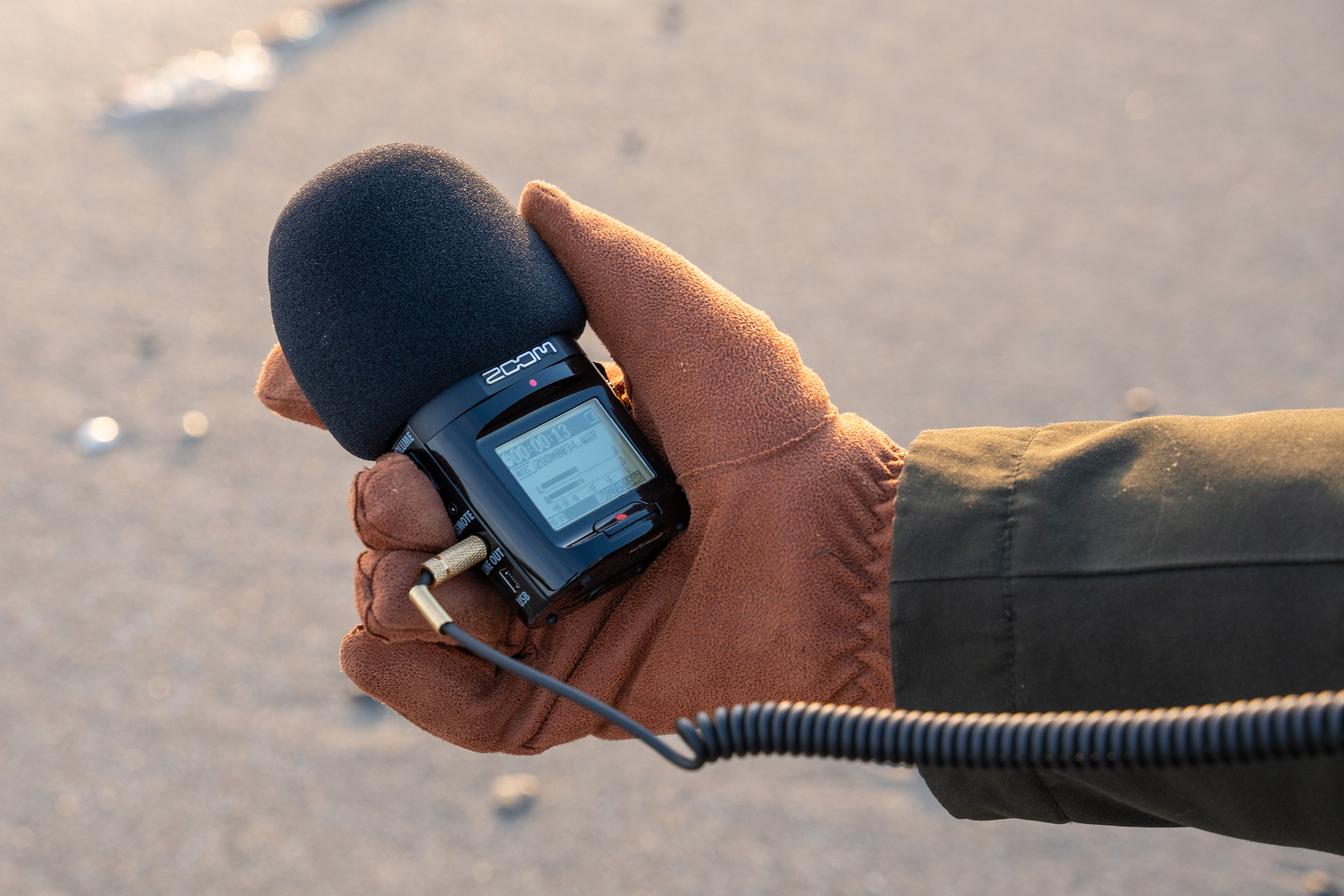 a gloved hand holds a high-tech audio recorder