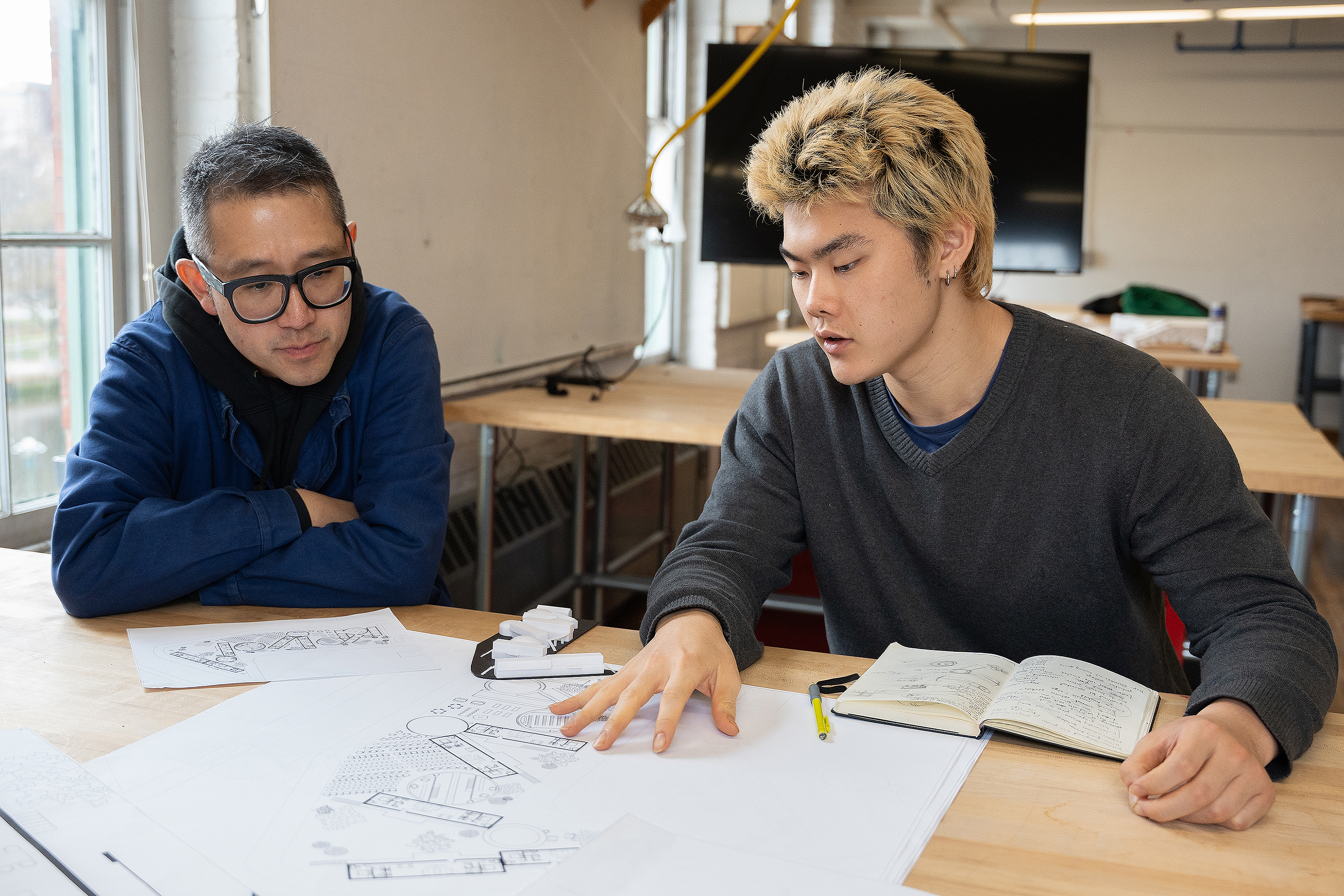 Architecture faculty member Ritchie Yao goes over design renderings with a student