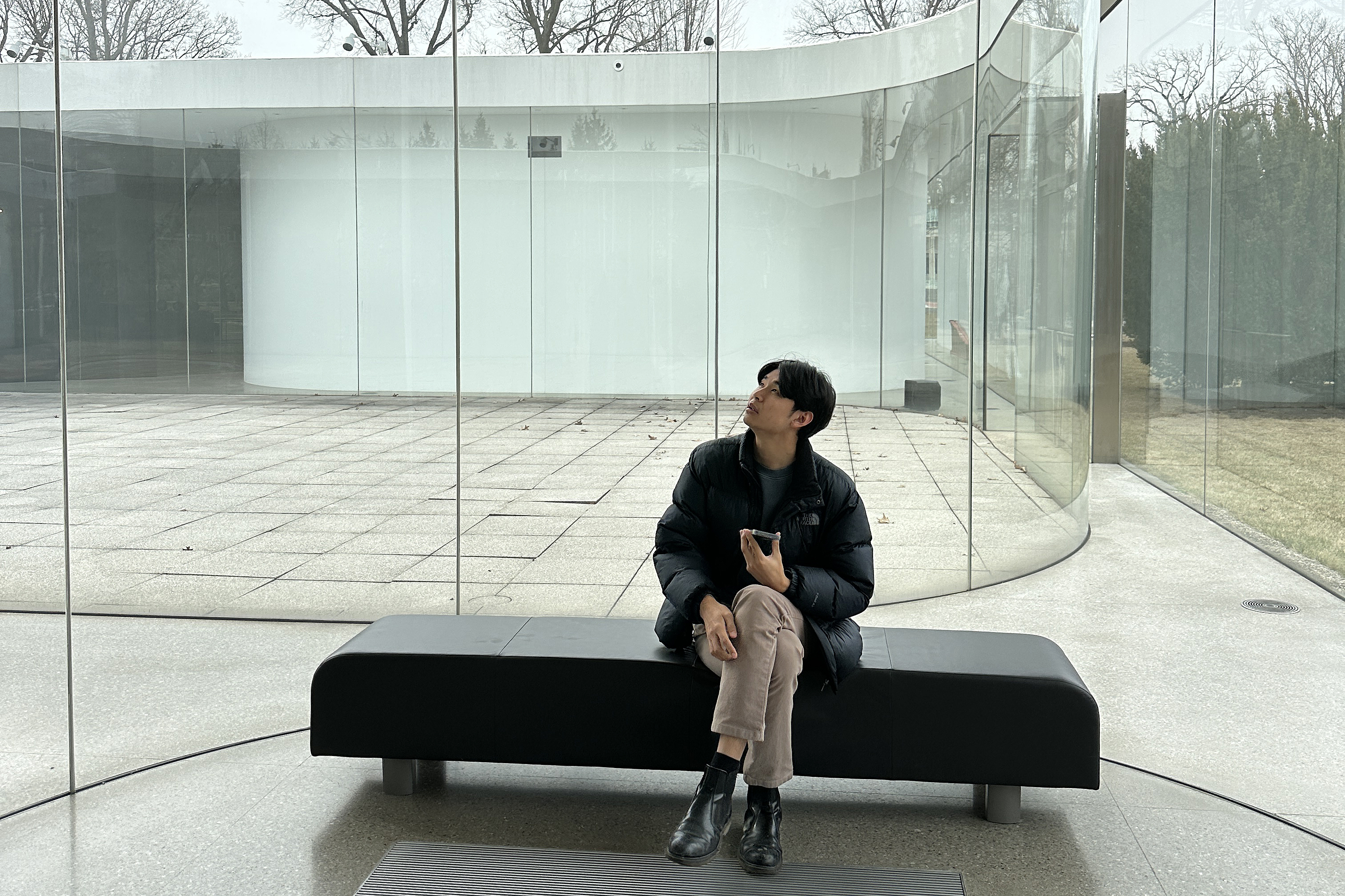 a student studies the curved glass walls at SANAA's Toledo Glass Pavilion in Ohio