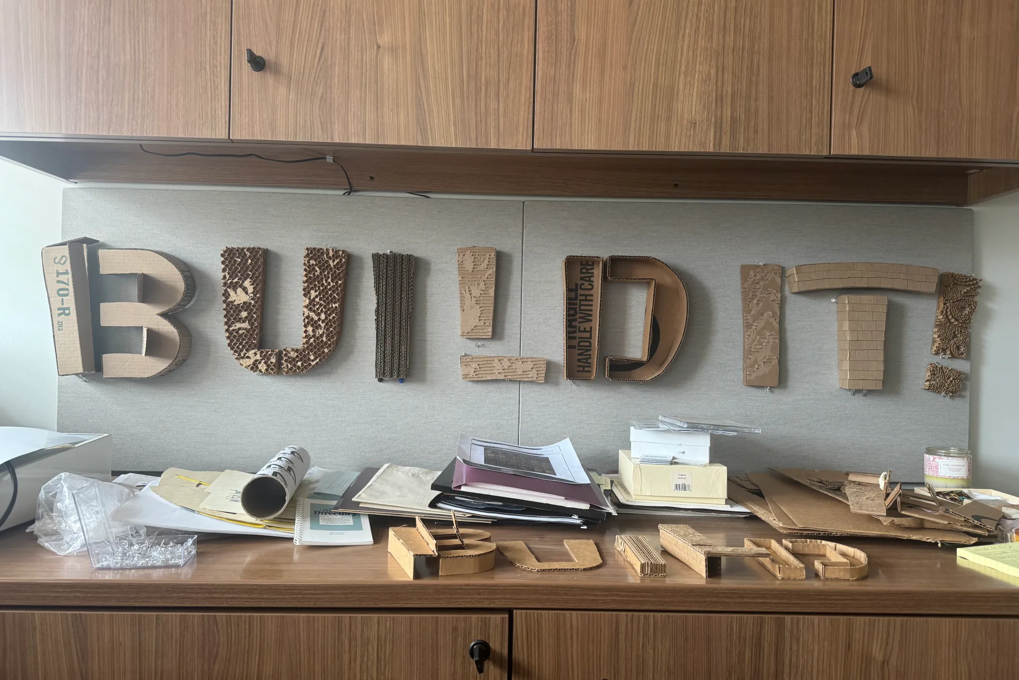 The words "build it!" spelled out in a cardboard design