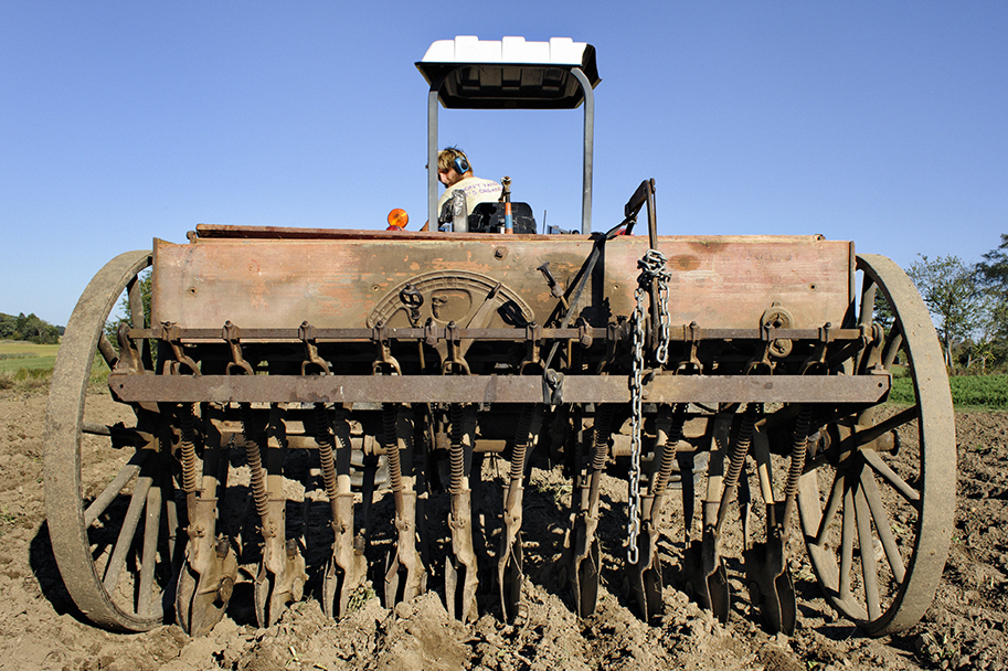 image of a farmer on an archaic-looking tractor